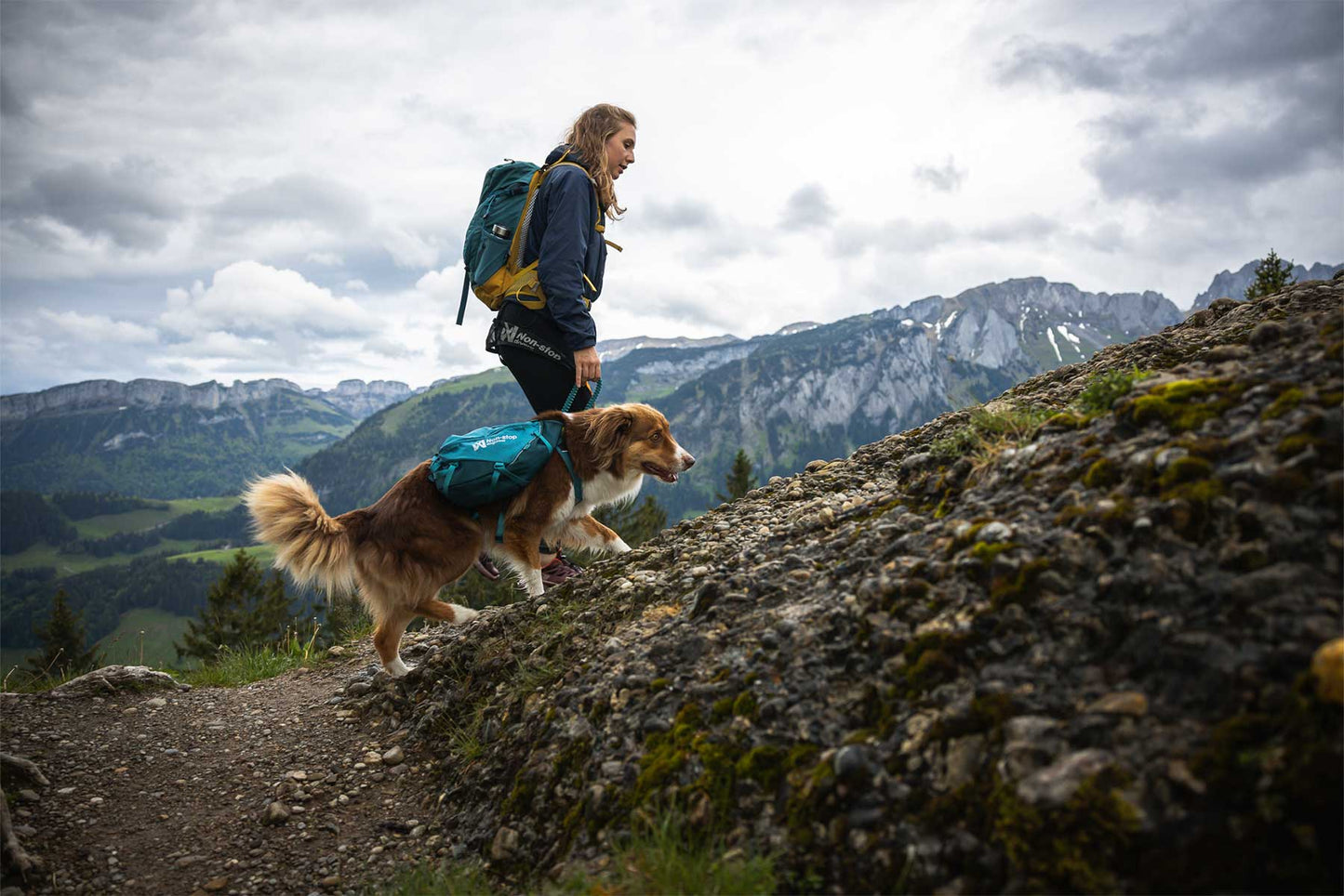 Chica ascendiendo una montaña con su perro y la mochila Non-stop dogwear Trail dog backpack