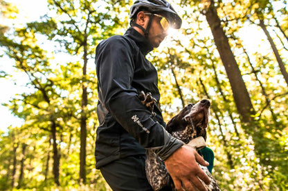 Hombre con su perro utilizando la chaqueta Non-stop dogwear Canix warm up jacket