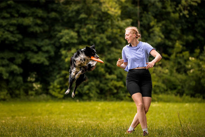 Perro cogiendo el aire el frisbee que lanza su tutora