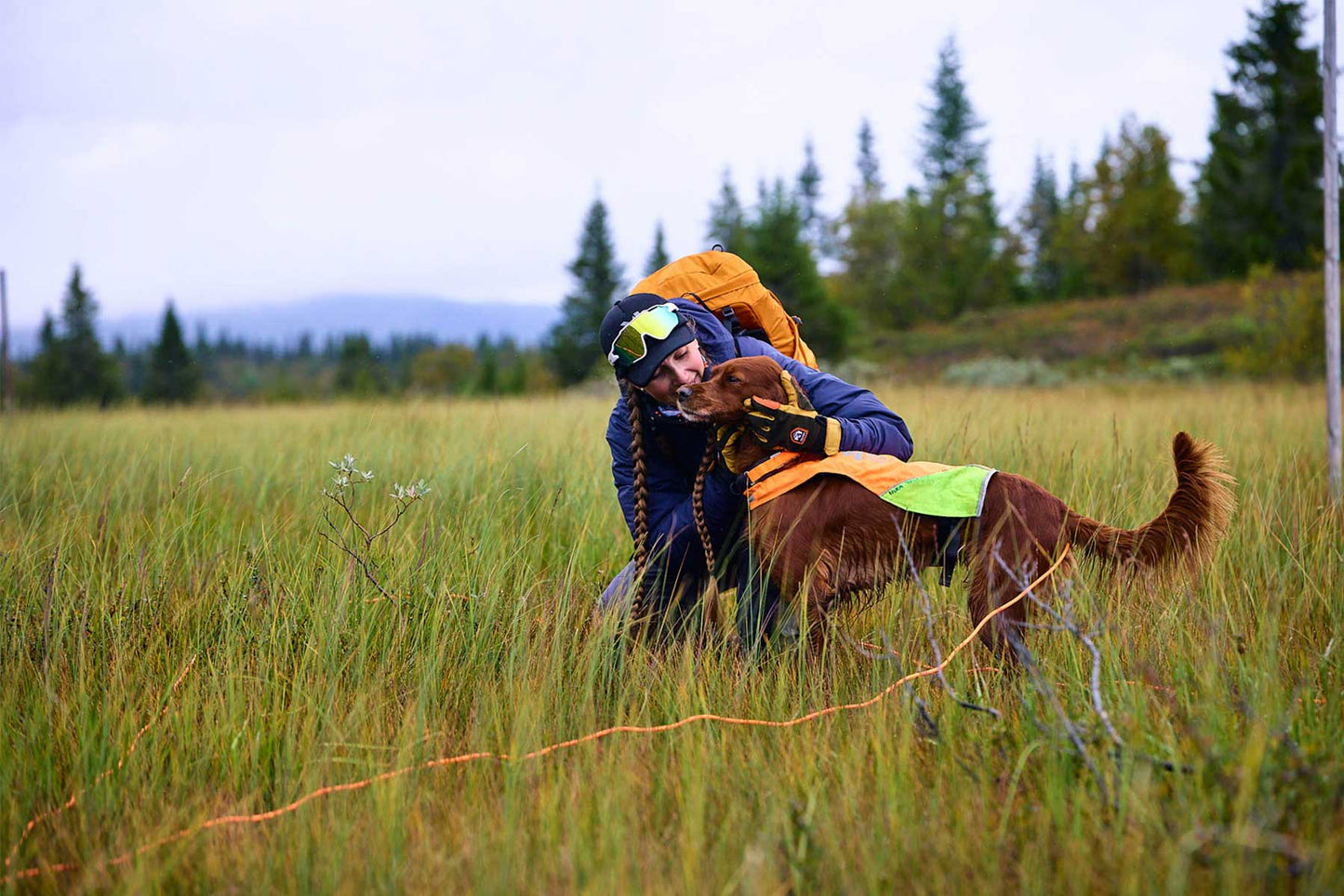 Chica dando un beso a su perro mientras usa una correa larga de Non-stop dogwear