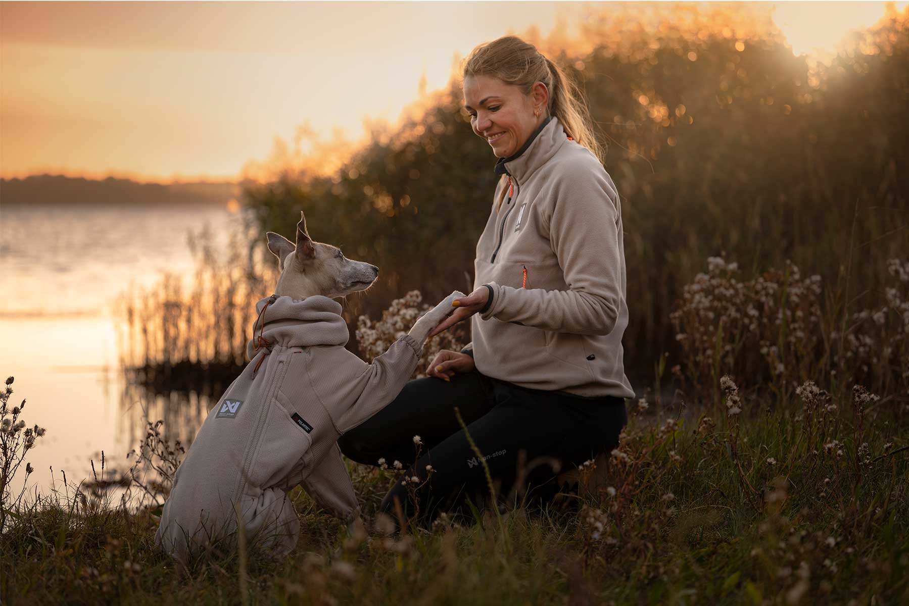 Chica y su perro al atardecer ambos llevando un polar de color beige